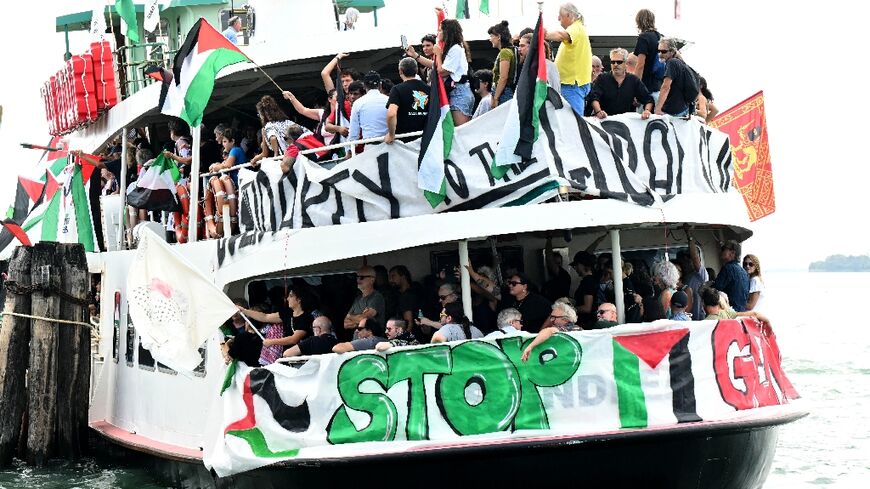 People aboard a boat wave Palestinian flags as they arrive to take part in a demonstration in support of Gaza at the Venice Lido 