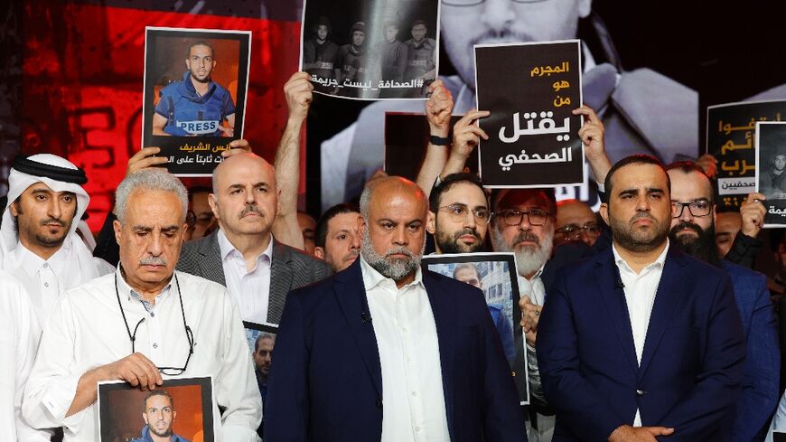 Wael Al-Dahdouh, Al Jazeera's Gaza bureau chief, stands with anchor and presenter Mohamed Krichen and presenter Tamer Almisshal during a moment of silence to honour five of their colleagues killed in an overnight Israeli strike in Gaza City