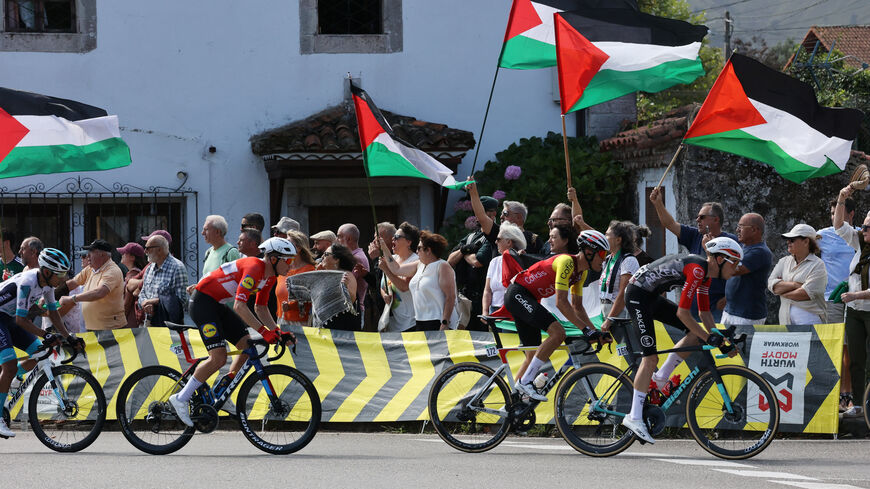 FILE PHOTO: Cycling - Vuelta a Espana - Stage 13 - Cabezon de la Sal to L'angliru - Cantabria, Spain - September 5, 2025  Riders pass protesters with Palestine flags during stage 13 REUTERS/Pankra Nieto/File Photo