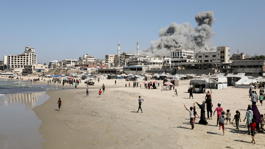 Palestinians walk as smoke rises from the evacuated Al-Ghefari tower, after it was hit by Israeli air strikes, in Gaza City, September 15, 2025. REUTERS/Dawoud Abu Alkas