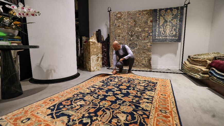 A man inspects a handmade rug in a carpet shop in northern Tehran