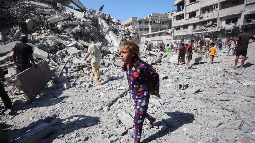 Displaced Palestinians salvage items from the rubble of the Al-Ghafari tower after it was destroyed in Israeli strikes in Gaza City