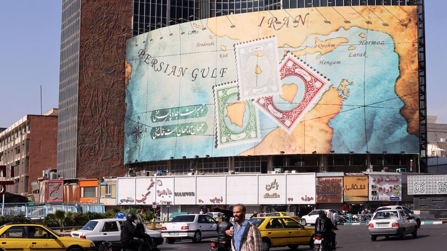 People walk and drive past a billboard depicting as postage stamps the disputed Abu Musa and Greater and Lesser Tunb islands in Tehran on Oct. 26, 2024.