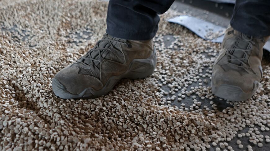 A member of the security forces with Syria's new government stands over pills of Captagon during a raid in Latakia on Jan. 19, 2025.