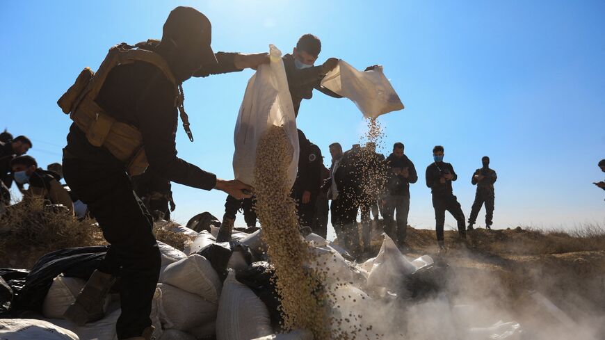 Members of Syria's new security forces empty sacks of Captagon into a ditch to burn them in a field on the outskirts of Damascus, on Jan. 19, 2025.