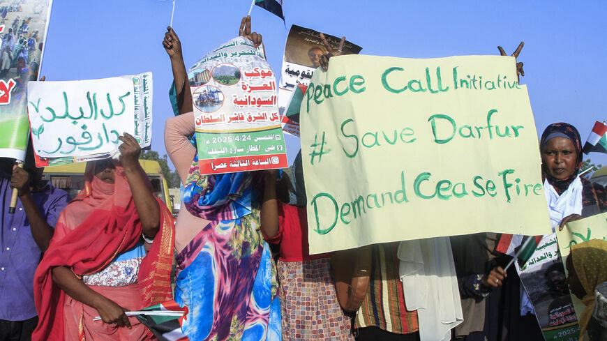 People lift national flags and placards during a rally called for by Sudan's Popular Front for Liberation and Justice in Port Sudan on April 24, 2025, to denounce the siege imposed by the paramilitary Rapid Support Forces (RSF) on El-Fasher city and express support for its residents. 