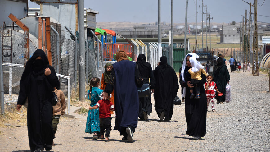 Women and children walk at the Al-Amal Camp (formerly Al-Jadaa), south of Mosul in northern Iraq, which houses Iraqi families who have been repatriated from Syria's Al-Hol camp, on May 8, 2025.