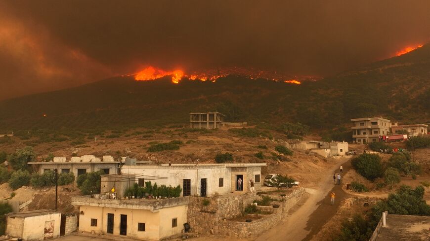 Residents of the village of Shatha watch as a wildfire rages on the nearby hills, in the western Hama countryside in west-central Syria on Aug. 15, 2025.