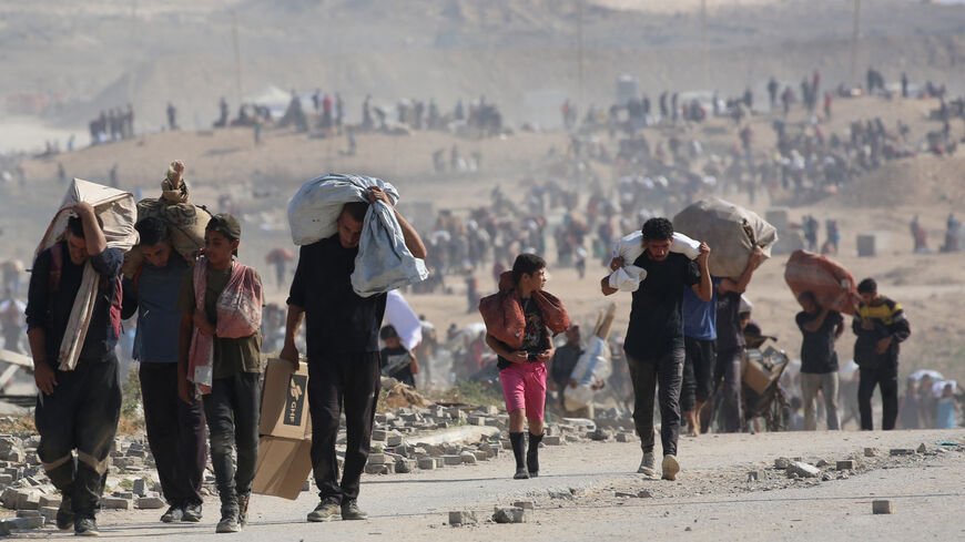 Palestinians walk with bags of humanitarian aid they received at a distribution centre run by the US and Israeli-backed Gaza Humanitarian Foundation (GHF), at the so-called "Netzarim corridor", in Nuseirat in the central Gaza Strip, on Sept. 26, 2025.