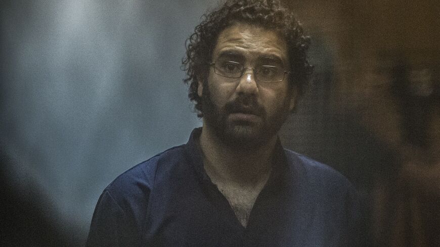 Egyptian activist and blogger Alaa Abdel Fattah looks on from behind the defendant's cage during his trial for insulting the judiciary alongside 25 other defendants including ousted Egyptian president Mohamed Morsi, who was recently sentenced to death, in Cairo on May 23, 2015. 