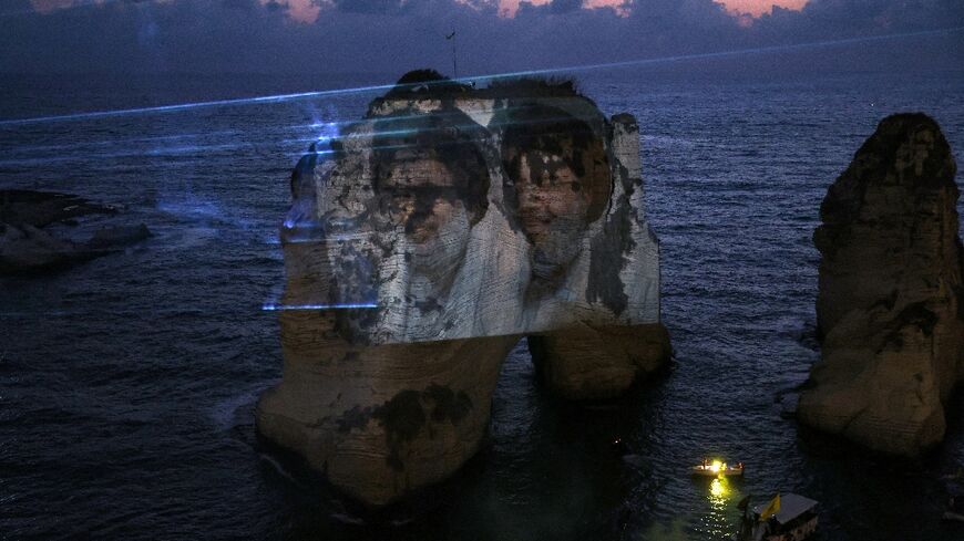 The portraits of slain Hezbollah leaders Hassan Nasrallah (R) and Hashem Safieddine are projected against Beirut's landmark Raouche Rock