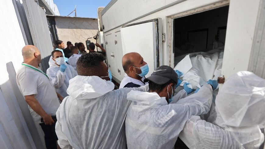 Morgue workers unload the bodies of Palestinians that had been in Israeli custody, after they were transported by Red Crescent vehicles and refrigerated trucks to Khan Yunis in the Gaza Strip