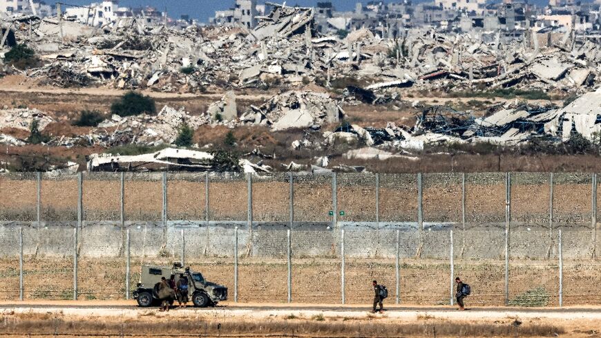 Israeli army soldiers walk towards an armoured vehicle at a position along the border fence with the Gaza Strip in southern Israel 