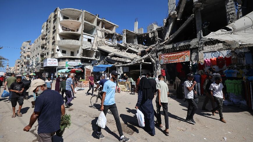 Palestinians walk past a destroyed building in Gaza's Nuseirat refugee camp