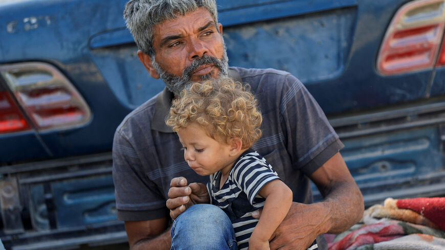 Palestinian man Faraj al-Ghalayini, who fled Gaza City recently due to an Israeli military operation with his wife Nancy Abu Matroud, who went into labor while moving south then gave birth prematurely to twins who later died, holds their daughter Etra, a cancer patient, as they shelter by a roadside, in the central Gaza Strip September 26, 2025. REUTERS/Dawoud Abu Alkas