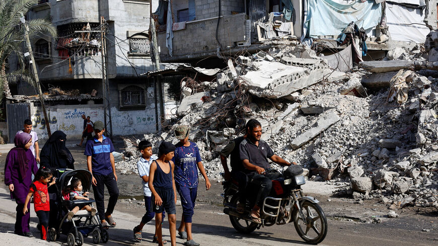 Palestinians walk past a residential building destroyed in previous Israeli strikes, after Hamas agreed to release hostages and accept some other terms in a U.S. plan to end the war, in Nuseirat, central Gaza Strip October 4, 2025. REUTERS/Mahmoud Issa
