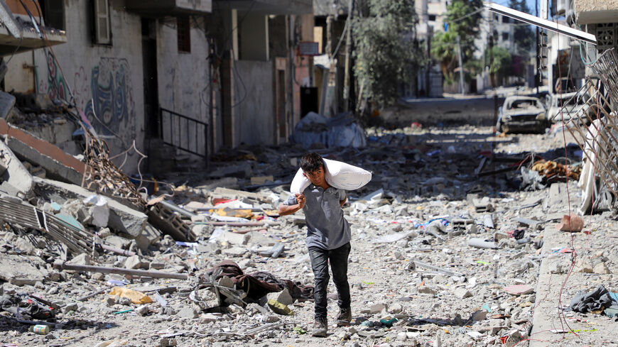 Palestinian boy carries a bag with flour at Sabra neighbourhood, following Israeli operation, in Gaza City, October 8, 2025. REUTERS/Ebrahim Hajjaj
