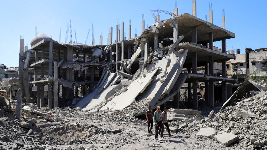 Palestinians walk past a destroyed building, as they inspect the damage in the aftermath of Israeli operation at Sabra neighbourhood in Gaza City, October 8, 2025. REUTERS/Ebrahim Hajjaj     TPX IMAGES OF THE DAY