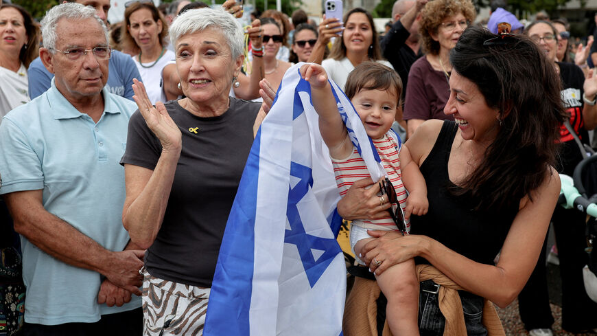A child, with an Israeli flag draped around its shoulder, reacts as people gather to celebrate at the "Hostages square" after U.S. President Donald Trump announced that Israel and Hamas agreed on the first phase of a Gaza ceasefire, in Tel Aviv, Israel, October 9, 2025. REUTERS/Ronen Zvulun