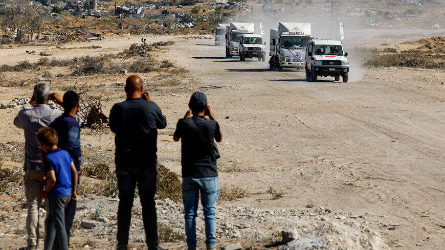 People look at Red Cross vehicles as they escort trucks transporting the bodies of deceased Palestinians held by Israel during the war, after their release, amid a ceasefire between Israel and Hamas, in Khan Younis, southern Gaza Strip, October 15, 2025. REUTERS/Mahmoud Issa