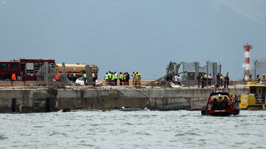 Emergency personnel gather near damaged fencing after a cargo plane veered off the runway during landing at Hong Kong International Airport in Hong Kong, China, October 20, 2025. REUTERS/Tyrone Siu