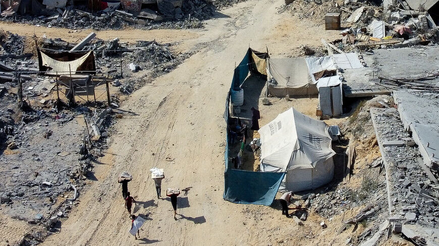 Palestinians walk past a tent amid the rubble in a destroyed area, amid a ceasefire between Israel and Hamas in Gaza, in Gaza City. REUTERS/Dawoud Abu Alkas