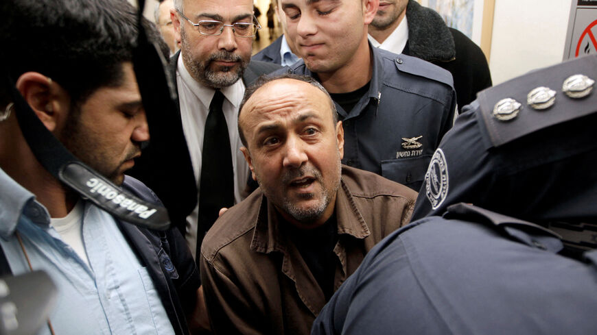 FILE PHOTO: Jailed Fatah leader Marwan Barghouti (C) is accompanied by Israeli prison guards after a deliberation at Jerusalem Magistrate's court January 25, 2012. Convicted of murder for his role in attacks on Israelis, Barghouti was jailed for life by Israel in 2004. REUTERS/Ammar Awad/File Photo