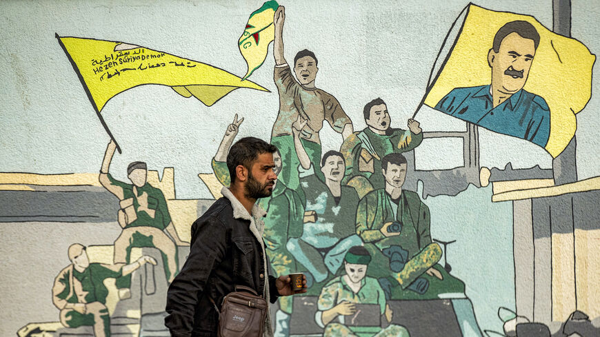 A man walks past a mural depicting supporters of the Syrian Democratic Forces (SDF), one of them raising a flag showing the face of Abdullah Ocalan — founding member of the militant Kurdistan Workers' Party (PKK) outlawed by Turkey, in Syria's northeastern city of Qamishli on Dec. 16, 2024.