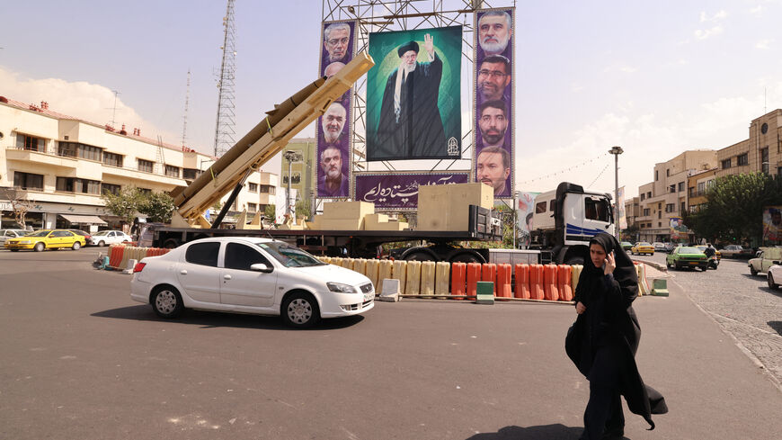 A woman walks past a deactivated Kheibar Shekan ballistic missile in front of a picture of Iran's Supreme Leader Ayatollah Ali Khamenei in Tehran's Bahrestan Square on Sept. 27, 2025, as part of an exhibit to mark the "Sacred Defense Week" commemorating the 1980-88 Iran-Iraq war. 