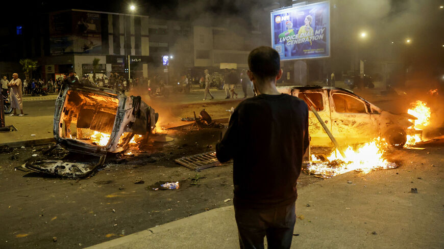 People look at police vehicles set on fire during a youth-led demonstration demanding reforms in the healthcare and education sectors in Sale on Oct. 1, 2025. 