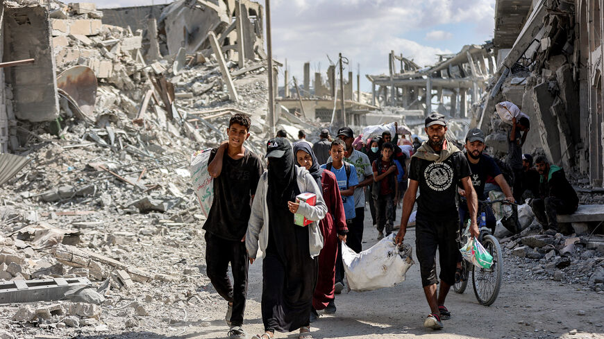 People walk along a destroyed road past heavily-damaged buildings in the centre of Khan Yunis in the southern Gaza Strip on Oct. 10, 2025, as the displaced return to their homes after Israeli forces' withdrawal.