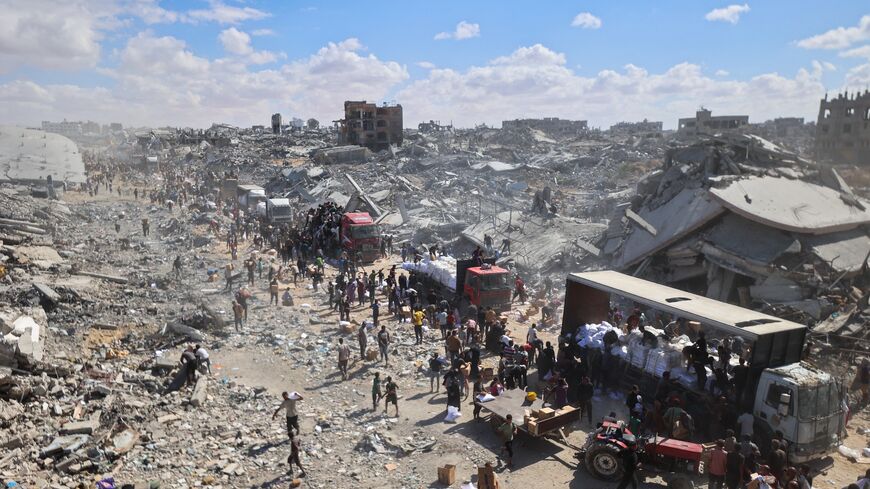 Palestinians rally around aid trucks which entered from the Karem Abu Salem crossing, in Khan Yunis in the southern Gaza Strip on Oct. 12, 2025.