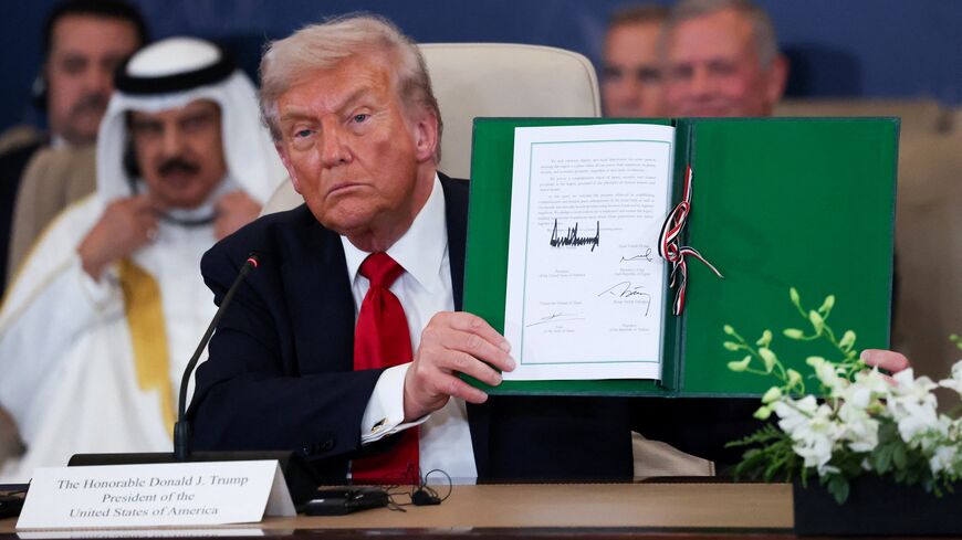 President Donald Trump poses with the signed agreement at a world leaders' summit on ending the Gaza war on Oct. 13, 2025, in Sharm el-Sheikh, Egypt. 