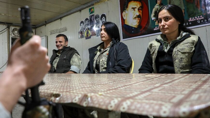 PKK members sit under a portrait of their jailed leader Abdullah Ocalan in a cave network in the Qandil mountains