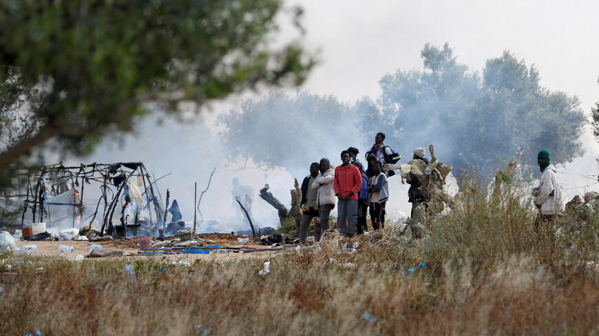FILE PHOTO: Migrants gather near burnt tents, as Tunisian authorities have dismantled makeshift camps housing sub-Saharan African migrants, in Amra, Sfax, Tunisia April 24, 2025. REUTERS/Zoubeir Souissi/File Photo