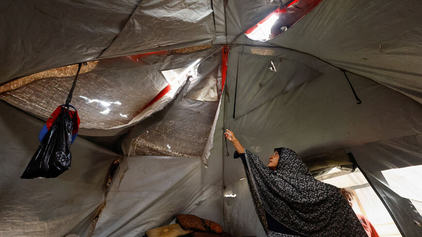 A displaced Palestinian woman shows her torn tent, amid a ceasefire between Israel and Hamas, in Gaza City, November 4, 2025. REUTERS/Mahmoud Issa