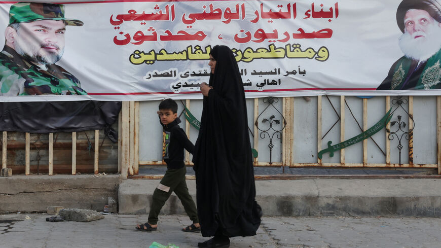 A woman walks past a banner showing Shi’ite cleric Muqtada al-Sadr and calling for a boycott of Iraq’s upcoming parliamentary elections in Sadr City, Baghdad, Iraq, November 3, 2025. REUTERS/Ahmed Saad