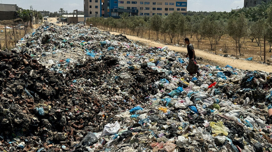 A Palestinian man walks on piles of garbage, amid the ongoing conflict in Gaza between Israel and Hamas, at Deir Al-Balah, in the central Gaza Strip, May 2, 2024. REUTERS/Doaa Rouqa