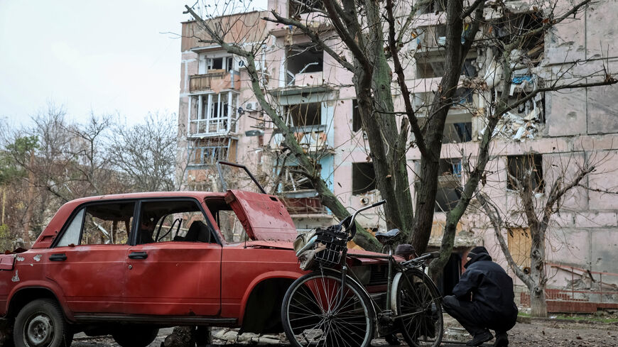 A resident hides from a Russian FPV drone behind a damaged car, amid Russia's attack on Ukraine, in the frontline town of Huliaipole in Zaporizhzhia region, Ukraine November 11, 2025. REUTERS/Sergiy Chalyi      TPX IMAGES OF THE DAY