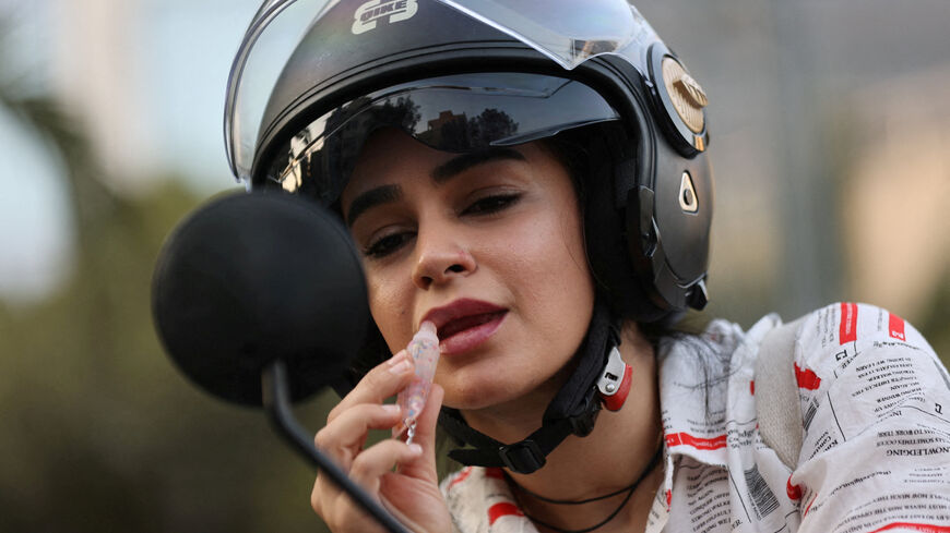 FILE PHOTO: An Iranian woman, Bahareh, applies lipstick while looking at herself in the mirror of her motorcycle while female motorcycling is still not officially legal, in Tehran, Iran, September 8, 2025. Majid Asgaripour/WANA (West Asia News Agency) via REUTERS/File Photo