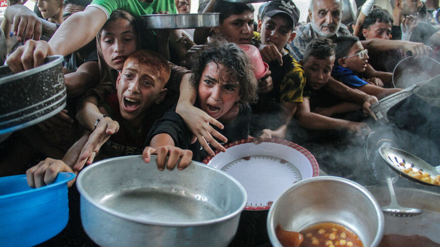 Palestinians gather to receive food cooked by a charity kitchen, amid the Israel-Hamas conflict, in the northern Gaza Strip, September 11, 2024. REUTERS/Mahmoud Issa