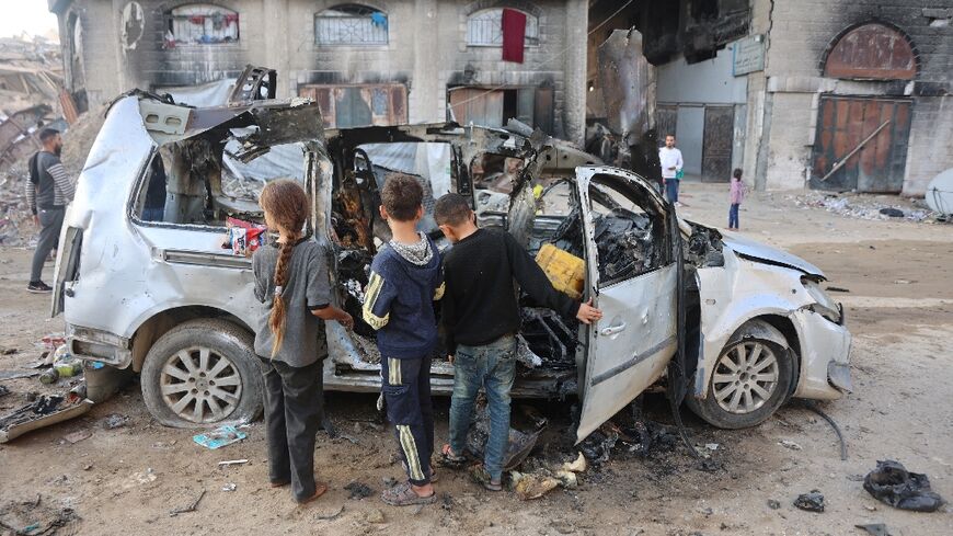 Palestinian children look at a destroyed vehicle in Gaza City