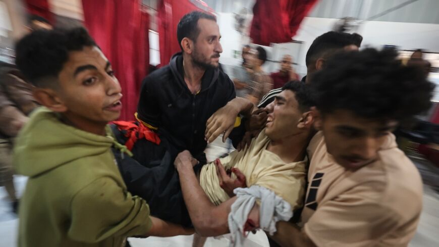 Palestinians carry an injured man at Al-Awda Hospital