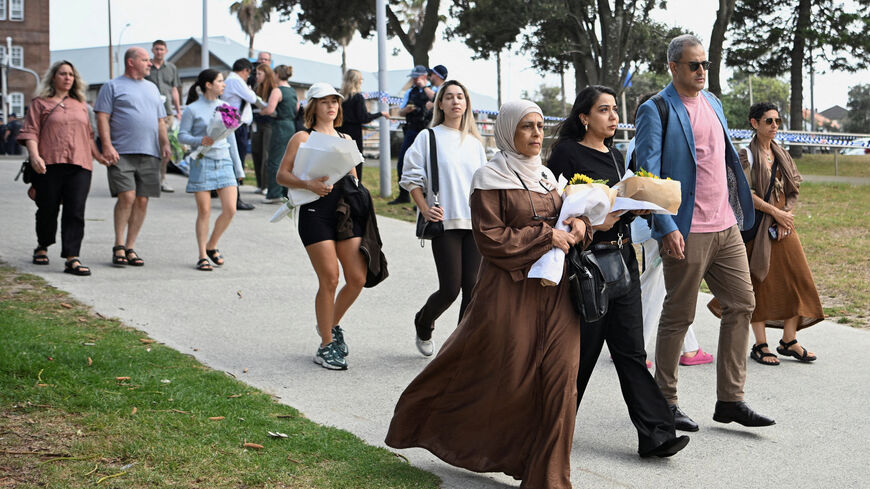People bring flowers for a makeshift memorial following the attack on a Jewish holiday celebration at Sydney's Bondi Beach, in Sydney, Australia, December 15, 2025. REUTERS/Flavio Brancaleone