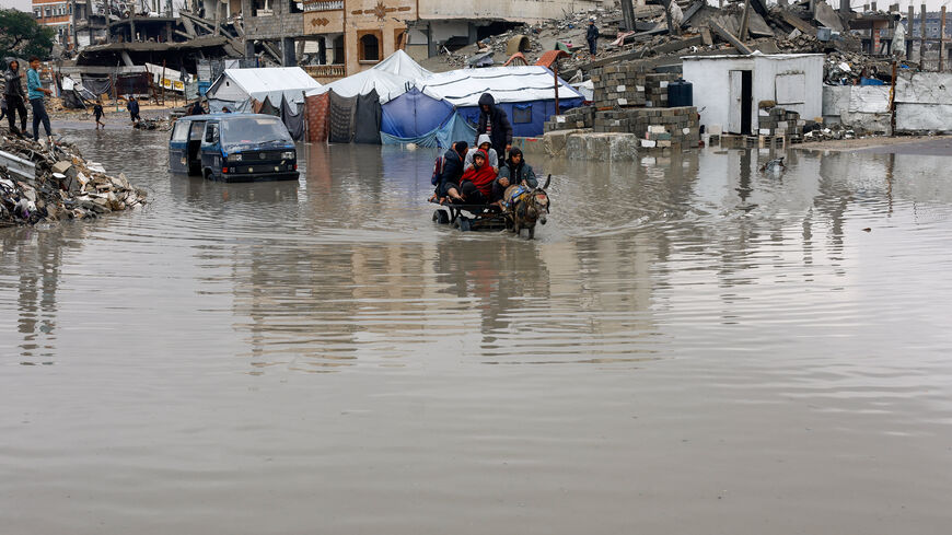 Displaced Palestinians ride a donkey-drawn cart on a rain-flooded street in Gaza City, December 12, 2025. REUTERS/Mahmoud Issa