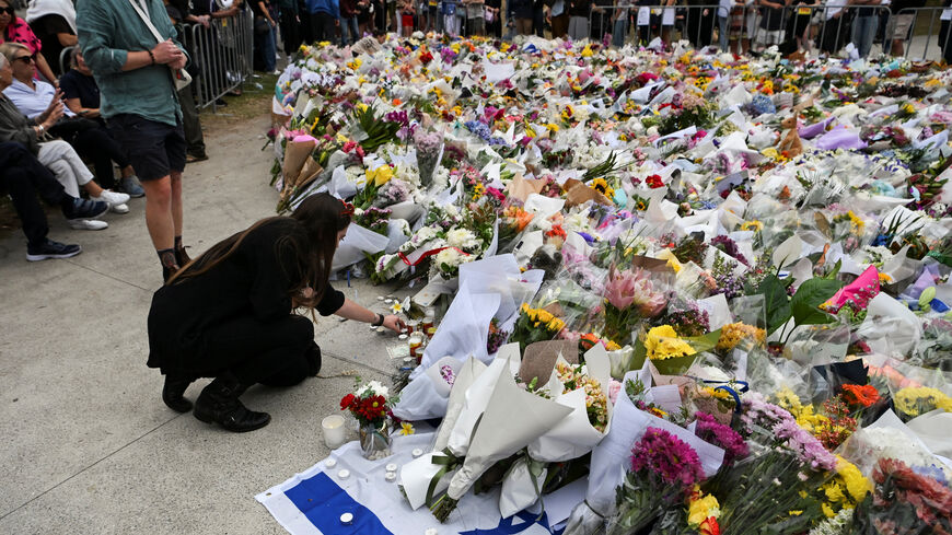 A woman keeps a candle next to flowers laid as a tribute at Bondi Beach to honour the victims of a mass shooting that targeted a Hanukkah celebration at Bondi Beach on Sunday, in Sydney, Australia, December 16, 2025. REUTERS/Flavio Brancaleone