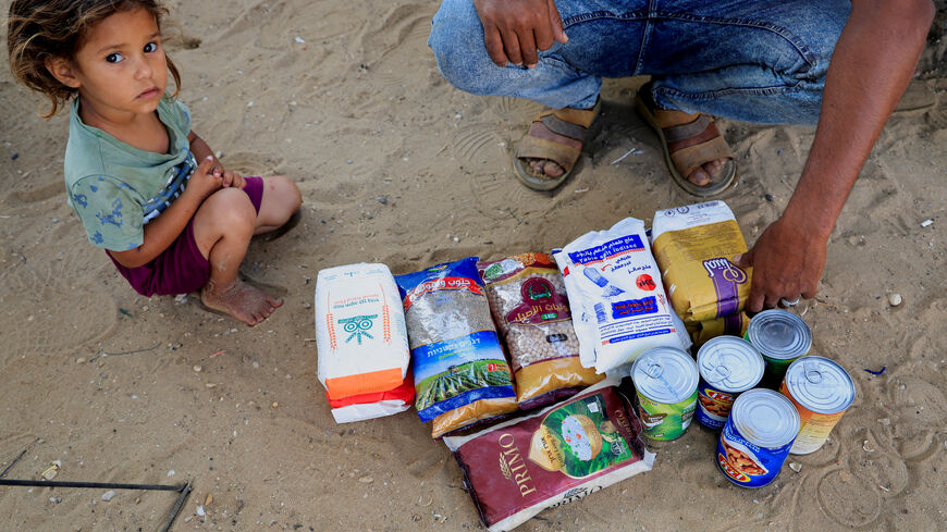 FILE PHOTO: A Palestinian man, next to a child, displays the aid supplies he received from the U.S.-supported Gaza Relief Organization, in Khan Younis, southern Gaza Strip, June 5, 2025. REUTERS/Hatem Khaled/File Photo