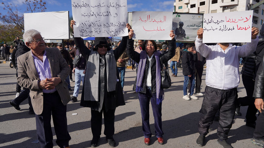 People from the Alawite sect hold up signs while protesting as they demand federalism and an end to what they say is the killing and violations against Alawites, in Latakia, Syria, December 28, 2025. REUTERS/Karam al-Masri