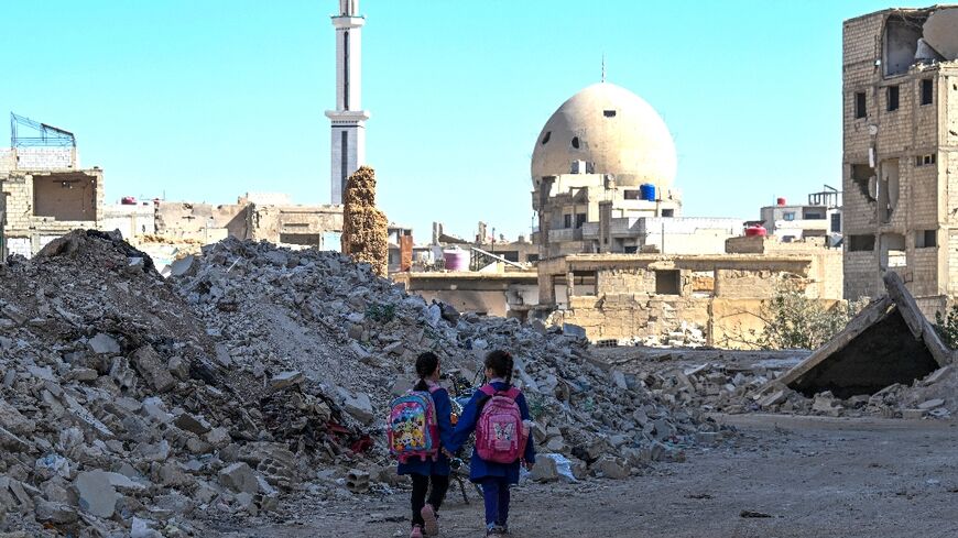Two Syrian girls walk to school through the ruin of Daraya