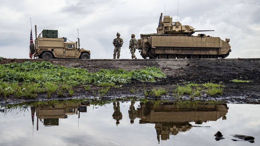 US Army soldiers stand near armored military vehicles on the outskirts of Rumaylan in Syria's northeastern Hasakah province, bordering Turkey, on March 27, 2023.